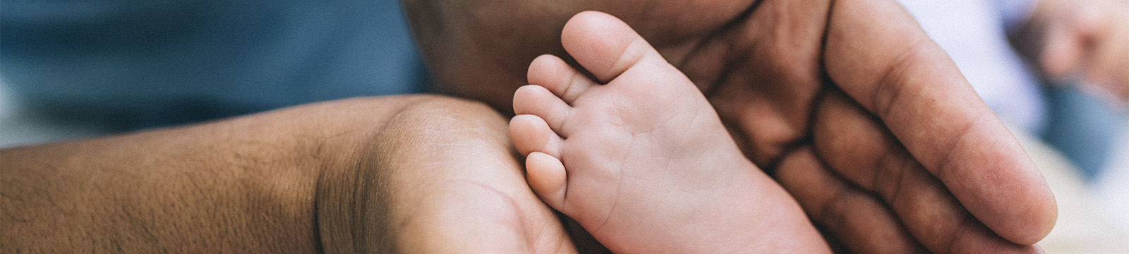 close up image of a father's hands holding newborn's foot.