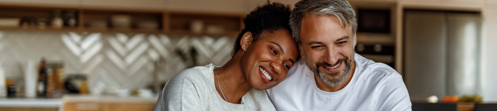 A couple leaning on each other and smiling in a kitchen