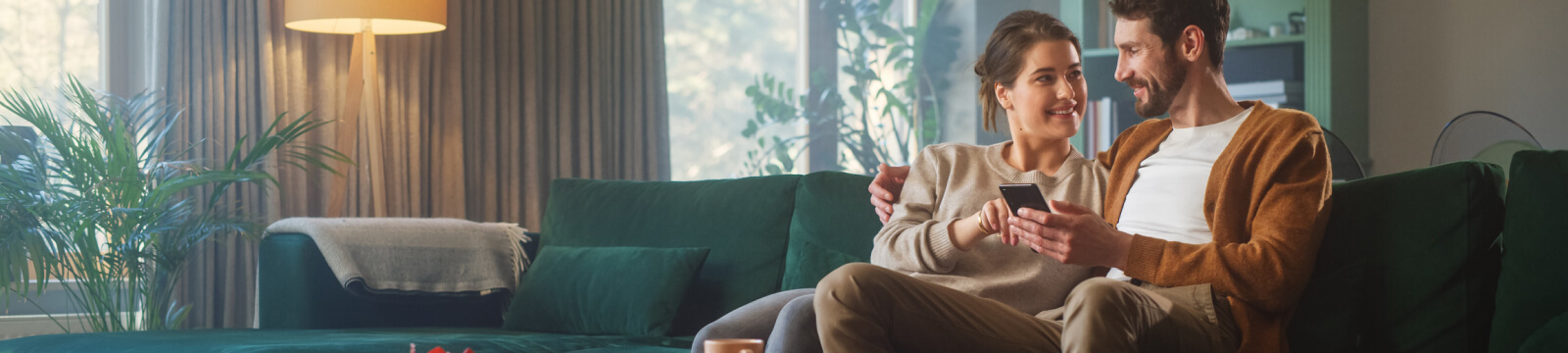 A couple sitting on a couch looking at a smartphone