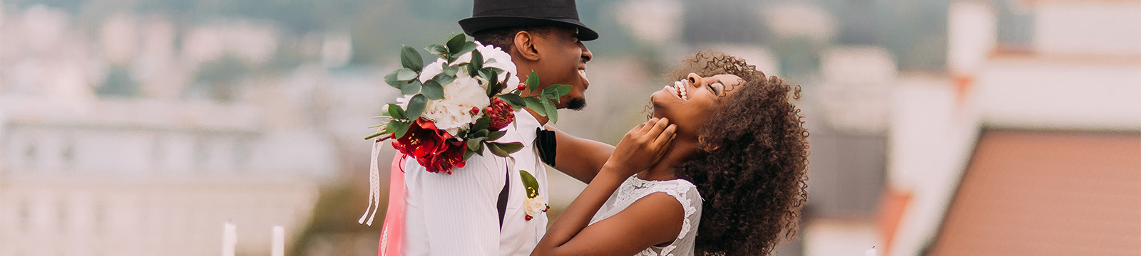 Smiling bride and groom wearing cool hat at outdoor reception