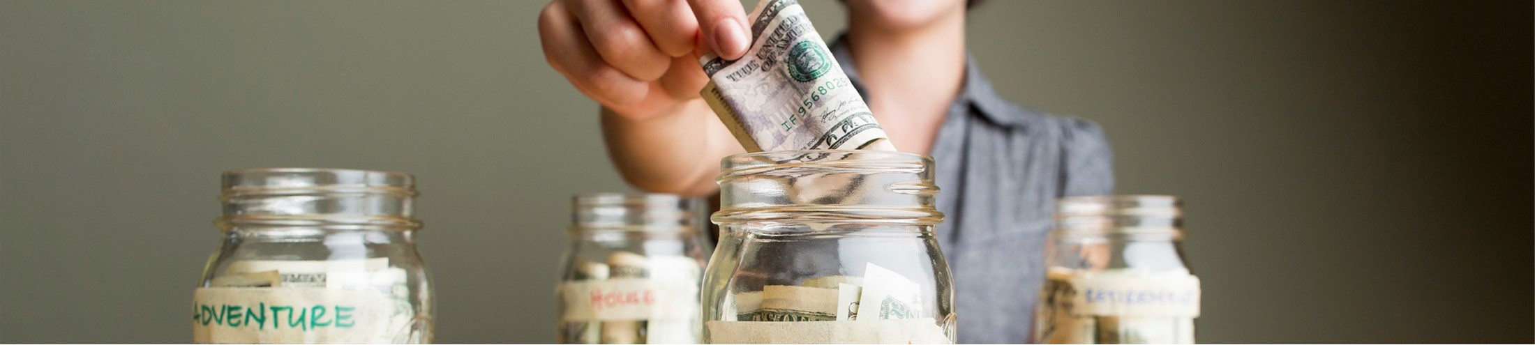 woman in background saving money into different labelled jars