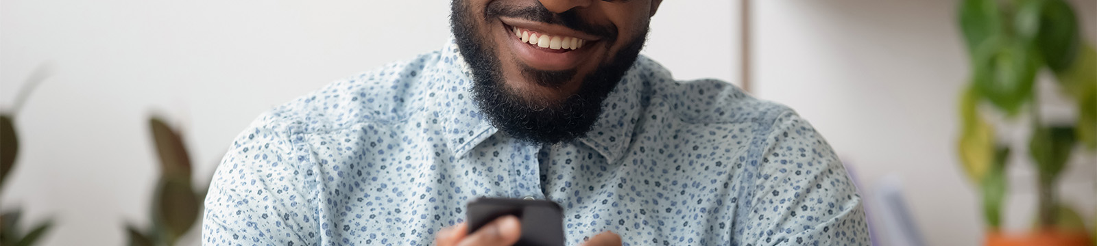 guy with beard smiling as he looks at this phone screen