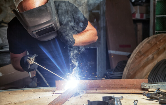 A worker wearing safety gear and sodering metal together