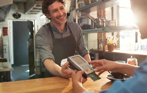 A man holds out a credit card reader for someone out of frame